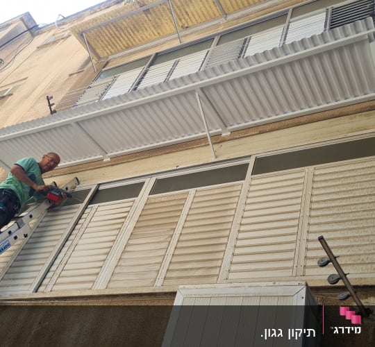 אדם על סולם מתקין גגון אלומיניום